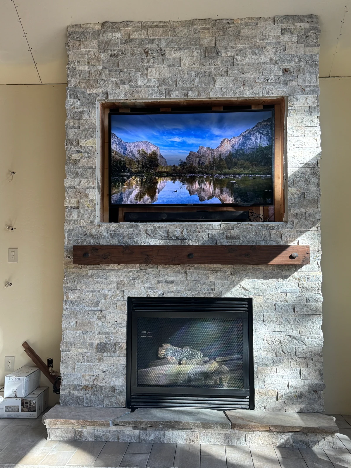 Stacked stone fireplace with reclaimed timber mantel by Monument Construction in Nevada County, CA